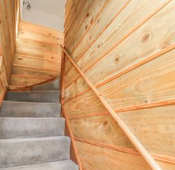 A carpeted staircase with wooden paneled walls and a wooden handrail at Seafield Granary in Alnmouth