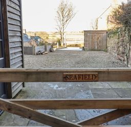 A view from a gate towards a gravel outdoor area at Seafield Granary Alnmouth
