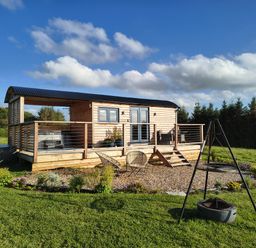 An outdoor area with a shepherd's hut and deck at Fir Tree Shepherd's Hut, Llanon