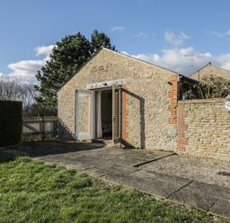 Stone cottage with open doors leading outside to a paved patio and grassy garden at South Barn Cottage in Hatford near Stanford In The Vale