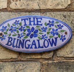 A blue and white sign with flowers reading The Bungalow on a brick wall at The Bungalow in Whitby