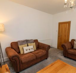 A living room with two brown sofas pillows a lamp a wooden door and a wooden table at The Bungalow in Whitby