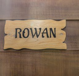 A wooden sign with the word Rowan on a wooden wall at The Rowan Pod in Cowbridge