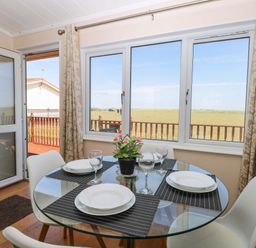 A dining room with a round table set for dinner at Boa Vista in Bacton
