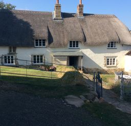 A thatched house with a garden and a gate at Westacombe Farm in Dunsford near Tedburn St Mary