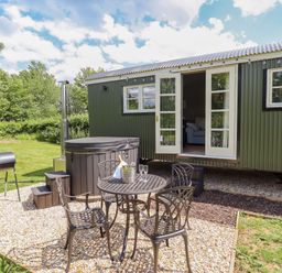 An outdoor space with a hot tub, table, chairs, and grill at Bluebell in Grimsby