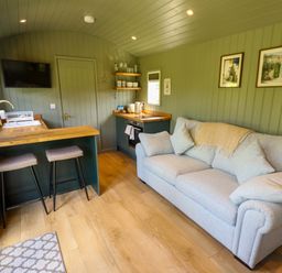 A living room with a couch and kitchen area at Bluebell in Grimsby