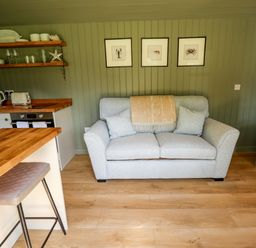 A living room with a sofa and kitchen counter at Primrose Grimsby