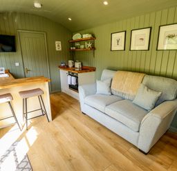 A living room with a sofa and kitchenette at Primrose in Grimsby