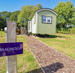A shepherd's hut with a pathway and sign at Magnolia in Grimsby