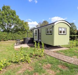 A shepherd's hut with outdoor seating and hot tub at Snowdrop in Grimsby