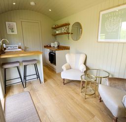 A living room with a kitchen counter and armchairs at Snowdrop in Grimsby
