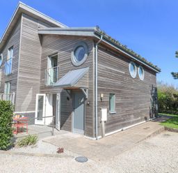 A wooden house with circular windows and an outdoor seating area at Azure Retreat at Una in Carbis Bay near St Ives