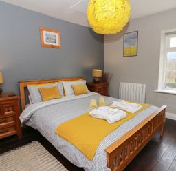 A bedroom with a wooden bed and yellow accents at Cantref House Top Floor in Brecon