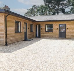 An exterior view of a wooden building with gravel at Barn Owl Lodge