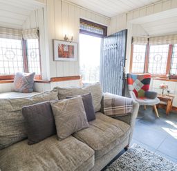 A sitting room with a gray sofa and colorful armchair by leaded windows at Bwthyn y Coediwr The Woodcutters Cottage in Tan Y Bwlch Maentwrog