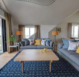 A living room with two sofas pillows a wooden coffee table a blue rug and lamps at Villa 4 Mullion