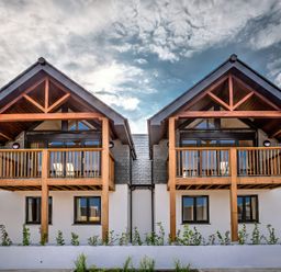 A double front view of two houses with wooden balconies and pitched roofs at Villa 5 in Mullion