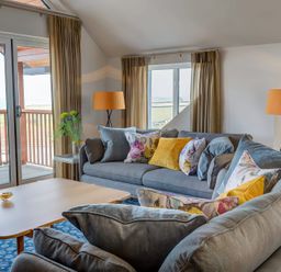 A living room with two sofas with cushions a wooden coffee table and two floor lamps at Villa 5 Mullion