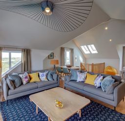 A living room with two sofas and a wooden table at Villa 5 Mullion