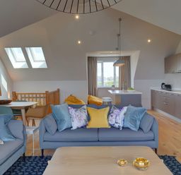 A living room with sofas and cushions next to a dining table and kitchen at Villa 6 in Mullion