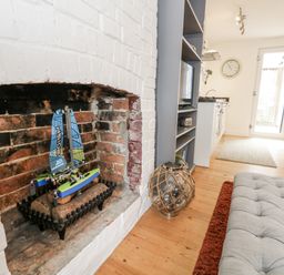 A living room with a model sailboat in the fireplace at Fisherman’s Cottage