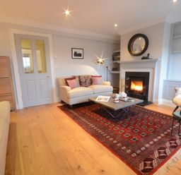 A living room with sofas a coffee table a fireplace and bookshelves at Sea Crest in Aldeburgh