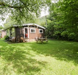 A cabin with a picnic table and chairs surrounded by grass at Ty Bedwen in Dinas Mawddwy