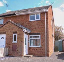 A brick semi detached house with white doors and windows next to a driveway and garage at Sweetacres in Hemsby