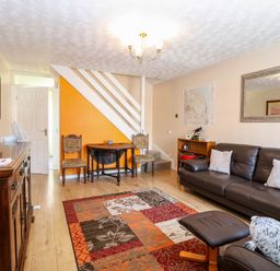 A living room with a sofa pillows a colorful rug wooden furniture and an orange accent wall at Sweetacres in Hemsby