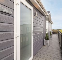 A porch with potted plants and a glass door on a grey building at The Gallops in Chipping Norton