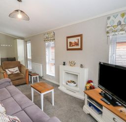 A living room with a sofa armchair coffee table television and fireplace at Lodge 2 in Auchterarder