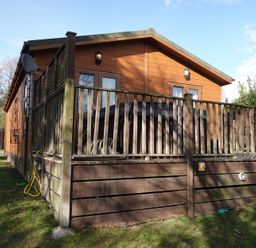 An outdoor view of a cabin with decking and a fenced area at Woodland View 31 - The Hawthorns Finlakes Holiday Park near Chudleigh