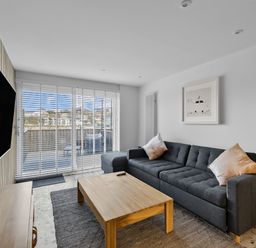 A living room with a gray sofa and wooden coffee table facing a wall-mounted TV at 5 Mermaid Court in Newquay