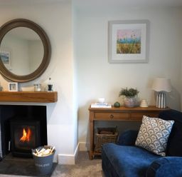 A living room with a fireplace and a blue armchair at Glendale in Trelights near Port Isaac