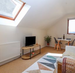 A living room with a television on a stand a small dining table with two chairs and a couch at Priory Barn Apartment Walton near Street