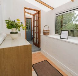 A hallway with a flower vase and wooden cabinet at Llain in Cardigan