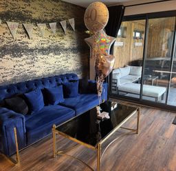 A living room with a blue sofa balloons and a black glass coffee table at Wayside Lodge in Blackpool