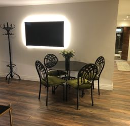 A dining area with a round glass table and four chairs with green cushions at Wayside Lodge in Blackpool