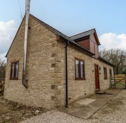 Exterior view of a stone house with multiple windows a door and a gravel driveway at Little Dairy House near Swanage