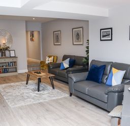 A living room with two sofas a wooden coffee table a bookshelf a round mirror and framed pictures on the walls at Daly's Place in Ballyporeen County Tipperary