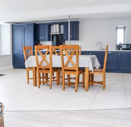 A kitchen with blue cabinets and a wooden dining table with six chairs at Daly's Place in Ballyporeen County Tipperary