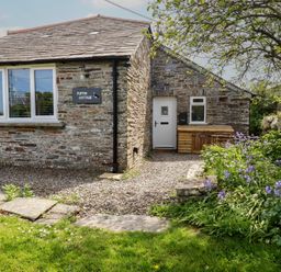 A house with a sign and flowerbed at Puffin Cottage in Tintagel