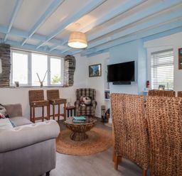 A living room with a guitar and a television at Puffin Cottage in Tintagel