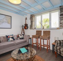 A living room with a map on the wall and a guitar at Puffin Cottage in Tintagel