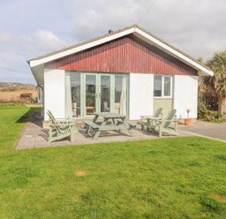 A patio with outdoor chairs and a picnic table in front of a house named Seafield in Rhydwyn near Cemaes Bay