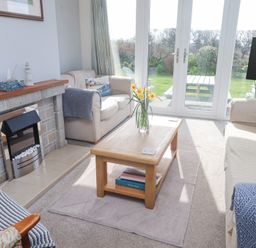 A living room with two sofas a wooden coffee table with flowers and a fireplace at Seafield in Rhydwyn near Cemaes Bay