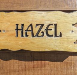 A wooden sign with the word Hazel carved on it attached to a wooden surface at The Hazel Pod in Cowbridge