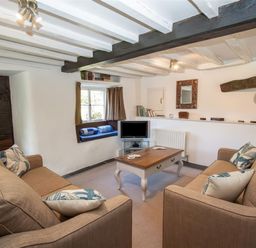 A living room with two sofas a coffee table a small television and a window seat at The Cragg in Hawkshead