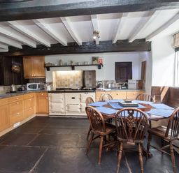 A kitchen with wooden cabinets round dining table wooden chairs and window seat at The Cragg in Hawkshead